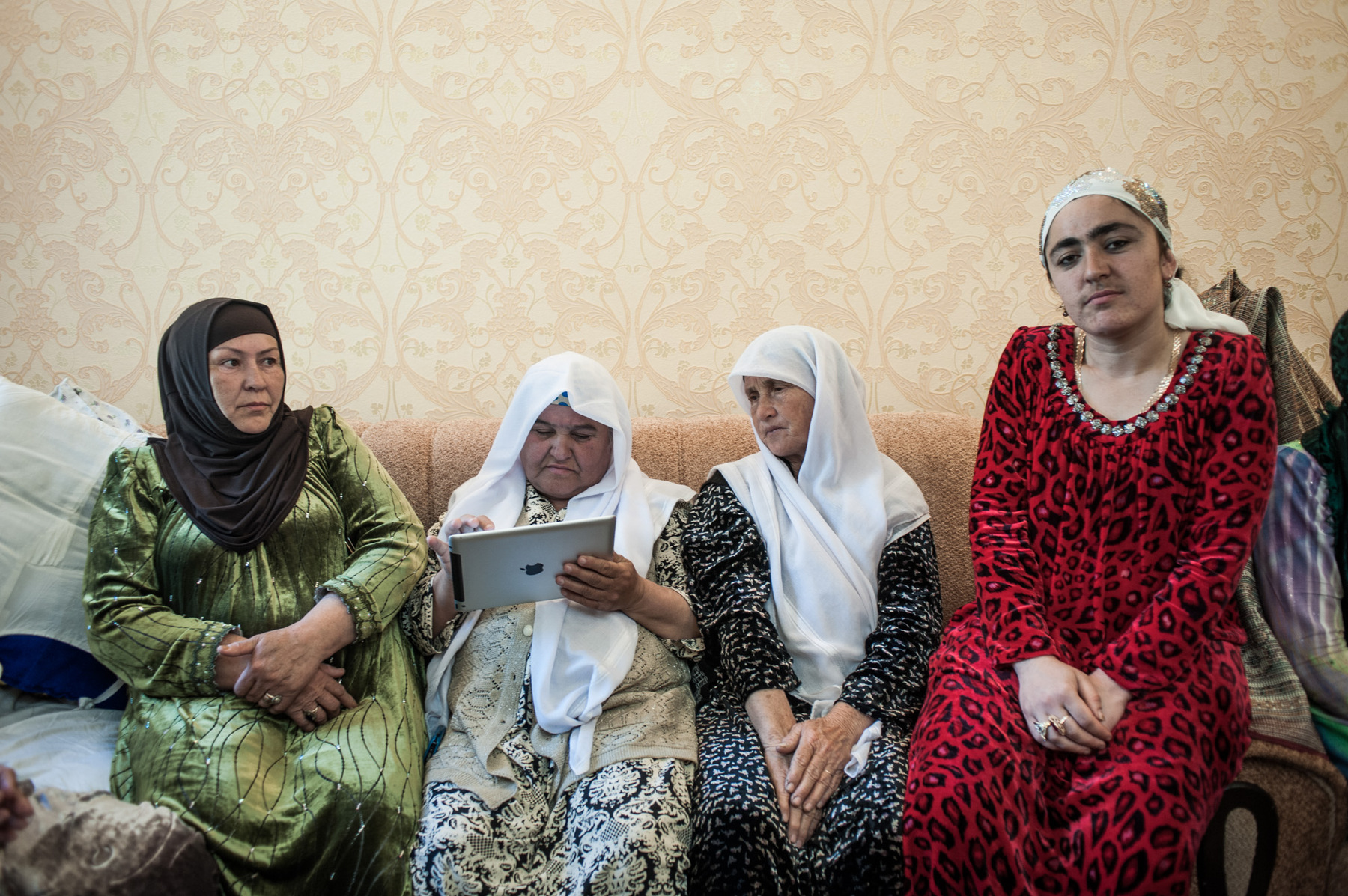Konstantin Salomatin - 09 Guests at the wedding. Women browse through guest ictures on iPad in order to make some match-making by looking at pictures of young men and women that would suit each other. Usially one wedding leads to 5-6 more. Sharora Village, Dushanbe region, Tajikistan, 2014.